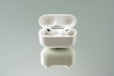 Ön tarafta kablosuz kulaklıklar sergilenen şarj çantasını aç. Yansıtıcı taban, minimum bir stüdyo ayarına derinlik katıyor..