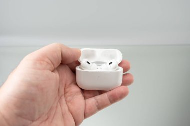 Açık bir şarj çantasının içindeki kablosuz kulaklıklar bir insanın elinde. Resim ölçek, taşınabilirlik ve günlük kullanım taşır.