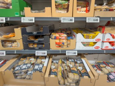 Almanya 29 Aralık 2025. Ekmek ruloları, ambalajlar ve paketlenmiş fırın ürünleriyle süpermarket rafı. Fiyat etiketleri ve günlük market eşyalarıyla düzenli perakende görüntüleme.