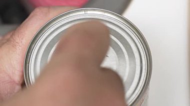 Mutfağa yakın çekimde bir kutu mısır elle açılır. Videoda yemek hazırlama ve günlük yemek malzemeleri vurgulanıyor