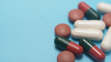 Mavi üzerinde fotokopi alanı olan haplar. Kapsüllerin ve tabletlerin fotokopi alanı ile mavi bir arkaplanda düzenlenmiş videosu. Tıbbi, ilaç ve sağlık geçmişi konsepti.