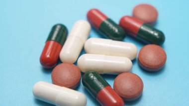 Mavi arka planda haplar. Mavi arka planda çeşitli hapların ve kapsüllerin makro videosu. Temiz tıbbi stile sahip ilaç ve sağlık konsepti.