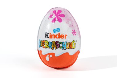 Üzerinde pembe çiçek olan bir Kinder yumurtası. Yumurta beyaz ve turuncu. Beyaz bir arka planda duruyor.