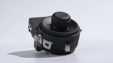 Otomotiv aynası kontrol düğmesi stüdyo ışığı altında düzgün dönüyor. Araba elektroniği, gösterge paneli parçaları ve yedek parçalar için ideal.
