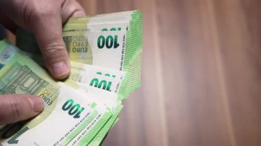 Avro Notlarının Aşırı Yakın Çekimi. Parmaklar tarafından sayılan 100 avroluk banknotların aşırı yakın çekimi. Doku, güvenlik özellikleri ve nakit detaylarına odaklan.