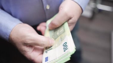 Avro Notaları Yakından Çeken Eller, yumuşak odaklı yakın plan çekimde 100 avroluk banknotlar tutuyor. Kişisel finans, likidite ve gerçek nakit işleme vurgusu.