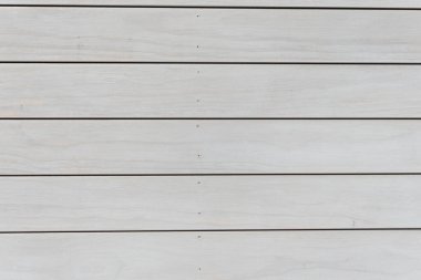 Üzerinde çizgiler olan beyaz tahta bir duvar. Hatlar eşit aralıklarla aralıklı. Duvar çok sade ve basit.