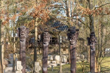 Ahşap oyulmuş figürler bahçe düzeninde duruyor. Geleneksel heykeller parka kültürel karakter ekler.