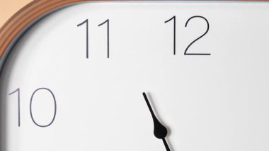 Minimalist bir analog saatin makro zaman çizelgesi. Kamera kadranda yavaşça soldan sağa hareket ederken siyah saat ilerlerken, rakamları ve zamanın geçişini vurguluyor..