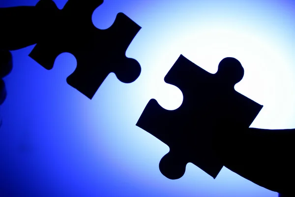 Hands connecting two jigsaw puzzle pieces