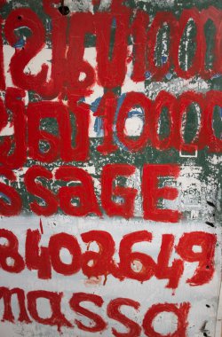 Vertical abstract MCU of hand painted foreign and English text on a sign reading 'Massage'