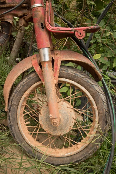 Vertical Medium shot of muddy front fork, wheel, and frame of light motorcycle