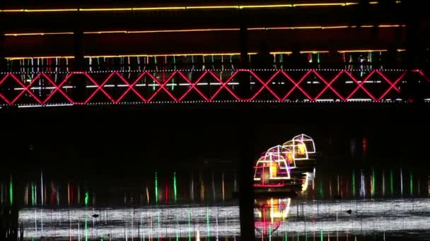 MS silhouettes people crossing illuminated footbridge at night in Asia — Stock Video