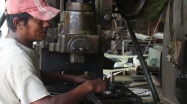 15 Mayıs 2016 -: Battambang, Cambodia: Orta yakın basın damgalama metal işçisi beslemeleri boşlukları kadar