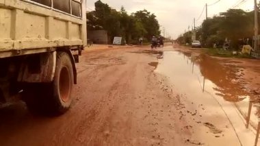 Siem Reap, Kamboçya - Temmuz 2016 yaklaşık: çukurlar ile kırsal Asya çamurlu yolda sürme Pov eylem cam görünümü