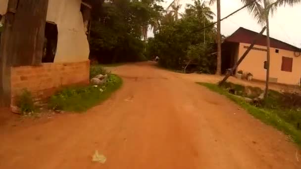 Siem Reap, Kambodża - około lipca 2016: Action cam widok jazda przeszłości domy w Azji na polnej drodze - krowa wyskakuje — Wideo stockowe