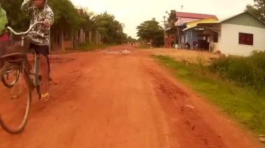 Siem Reap, Kamboçya - Temmuz 2016 yaklaşık: Bisiklet ve motos geçen Asya, çamurlu toprak kırsal yol aşağı sürme Pov
