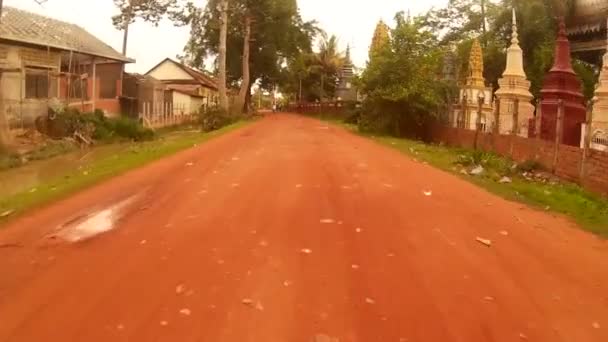SIEM REAP, CAMBOYA - CIRCA JULIO 2016: Action cam POV recorriendo el camino de tierra rural de Asia, pasando por la pagoda y las bicicletas — Vídeos de Stock