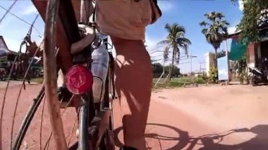 Siem Reap, Kamboçya - Temmuz 2016 yaklaşık: ağır çekim 60fps eylem cam Pov Asya Bisiklete binme kırsal yol palmiye ağaçları ile