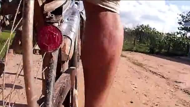 SIEM REAP, CAMBODIA - CIRCA JULHO 2016: Visão traseira ação cam POV Ásia ciclismo: Passe por pequena poça de lama estrada rural — Vídeo de Stock