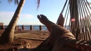 Orta görünüm kişi hamakta bacaklar deniz görünümü ve palmiye ağacı solda görünür olan haçlar