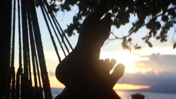 Mcu starke untergehende Sonne, die durch Zehen blinkt, wie in einer Hängematte gesehen — Stockvideo