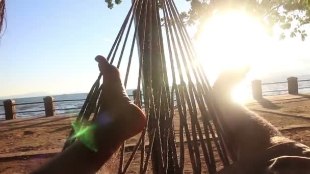 Los pies moviéndose en el sol en una hamaca junto al mar — Vídeos de Stock