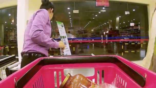 BANGKOK, TAILANDIA-CIRCA JULIO 2016: Supermercado: empleada saca comestibles de la canasta al momento de la compra — Vídeos de Stock