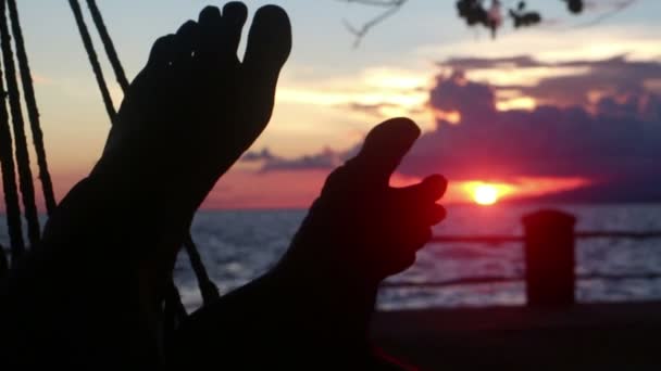 Medianos pies de CU retorciéndose en hamaca junto al mar al atardecer — Vídeos de Stock