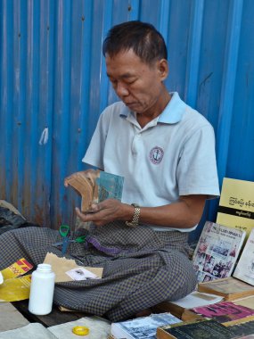 Yangon, Myanmar - 23 Aralık 2013: Street kitapçı iş yerini yakınındaki bir karton kapaklı kitap onarır