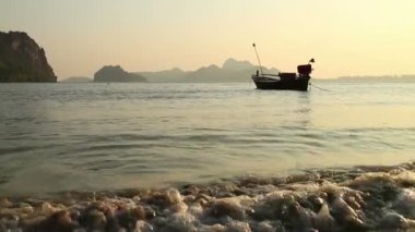 Güney Tayland'da sakin günbatımı koy su seviyesi görünümü, tek bir küçük balıkçı teknesi offshore demirlemiş dahil.
