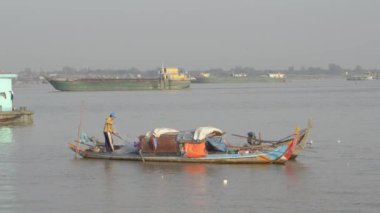 Arka planda dev yük gemisi ile küçük Asya ev yapımı tekne