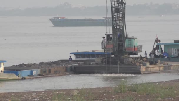 Construction Dredging: kraan schoppen zand van rivier met boot in de buurt — Stockvideo