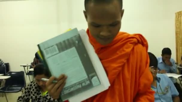 SIEM REAP, CAMBODIA: 12 СЕНТЯБРЯ 2015: Азиатские студенты сдают промежуточный экзамен, в котором молодой монах покидает экзамен — стоковое видео