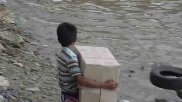 Kind brengt vak van goederen naar wachten boot — Stockvideo