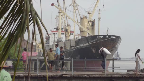 APRIL 26, 2014 - RANGOON, BURMA: Row of porters carry sacks at port with big ship — Stock Video