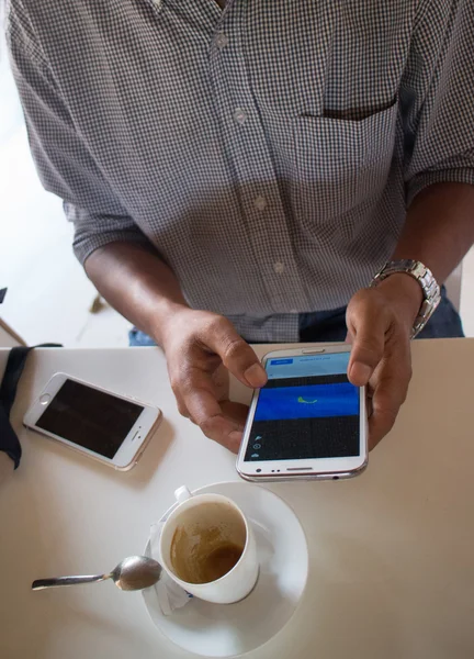 Bir akıllı telefon 'Phablet' bir café benzeri ortamda bakarak renk erkek bir kişinin yüksek açı orta vurdu