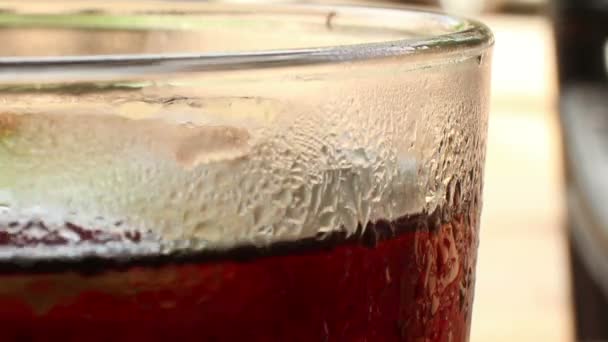 Ecu i toppen av ett glas cola-färgade kolsyrad dryck med oklar backgro — Stockvideo
