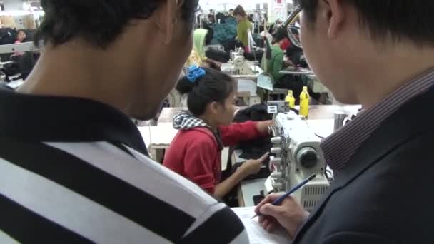 PHNOM PENH, CAMBODIA-SEPTEMBER 14, 2012: Textile Garment Factory: Supervisors watch garment worker at machine in factory — стоковое видео