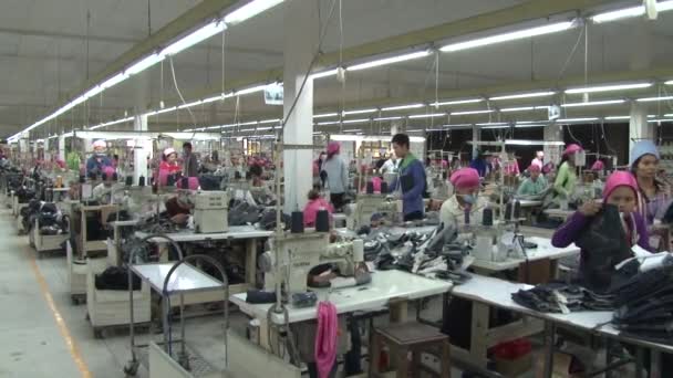 PHNOM PENH, CAMBODIA-SEPTEMBER 13, 2012: Textile Cloment Factory Workers: WS pan right to left on garment factory floor — стоковое видео