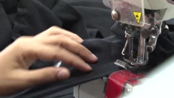 PHNOM PENH, CAMBODIA-SEPTEMBER 13, 2012: Textile Cloment Factory: CU hand places black fabric in sewing machine — стоковое видео