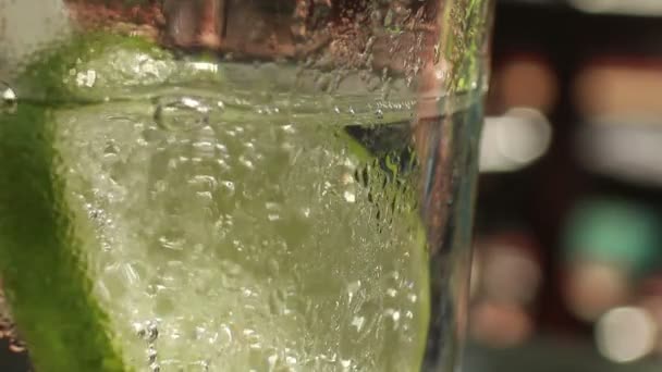 De Cu tonic macro met kalk terwijl persoon in een zwembad in de achtergrond spatten — Stockvideo