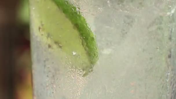 ECU pour cool tonic with lime & straw in a glass at a relaxing tropical setting — Stock Video