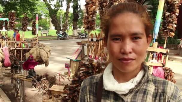 SIEAM REAP, CAMBODIA - DECEMBER 10, 2015: Medium close up shot of a female broom seller in Asia with her bicycle — Stock Video