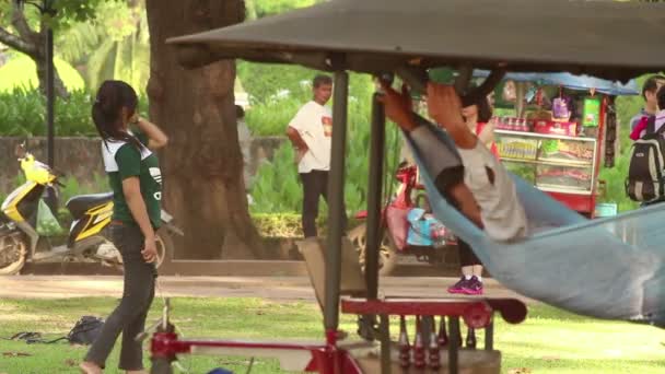 SIEM REAP, CAMBODIA - DEZEMBRO 10, 2015: Jovem joga badminton em um parque na Ásia com tuk tuk em primeiro plano — Vídeo de Stock