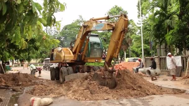SIEM REAP, CAMBODIA - JULY 23, 2015: Wide shot of a construction crawler shoveling dirt from a road — Stok Video
