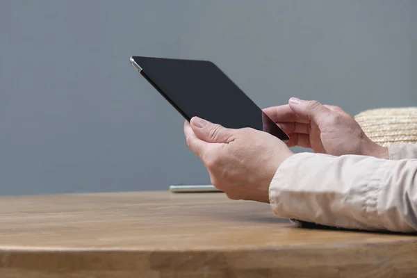 Bir adam kafedeki masada tablet tutuyor..