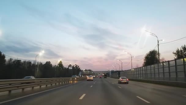 Kilátás az Autobahn a szélvédőn keresztül egy autó este fénye alatt lámpások hátterében egy gyönyörű ég. Lassú mozgás.. — Stock videók