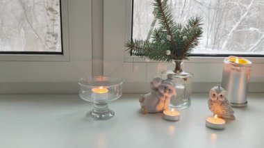 Pencerenin dışındaki karla kaplı ağaçların manzarasıyla evin pencere eşiğinde köknar ağacı kardan adam ve baykuşların Noel manzarası..