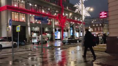 19.12.2020 Moskova Rusya manzarası. Sokakta insanlar ve Moskova 'nın göbeğinde Noel aydınlatmasıyla süslenmiş Merkez Mağazası yakınlarındaki bir trafik sıkışıklığında duran arabalar..